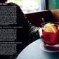 A close-up of a craft cocktail with an orange slice and ice sits in a glass on a coaster atop a table; nearby, a person with a patterned sleeve rests their arm. Instructions from The Classic Cocktail Sessions by Penguin Random House are visible, offering insight into mixology techniques.