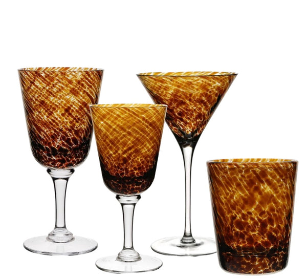 Four amber-colored textured glass drinkware pieces from the William Vanessa Tortoise Collection by William Yeoward Crystal, including a tall goblet, a medium goblet, a cocktail glass, and a tumbler, against a white background.