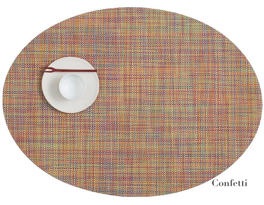 The Chilewich Oval Placemat in multicolored "Confetti" features a white plate, bowl, and brown chopsticks on the upper left—ideal for any dining occasion.