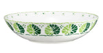 The Cobblers Cove Calypso Dinnerware Collection by Royal Crown Derby features a shallow white ceramic bowl adorned with vibrant green leaf patterns, creating a fresh Caribbean ambiance.