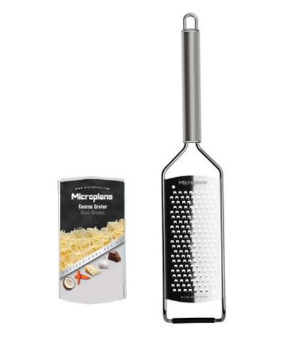 A Microplane Professional Series 2.0 stainless steel coarse grater with a long handle is displayed beside its box, which features images of grated cheese, nutmeg, and chocolate.