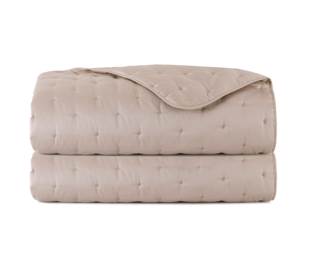 Folded taupe Triomphe Coverlet by Yves Delorme in luxury organic cotton with a tufted pattern.