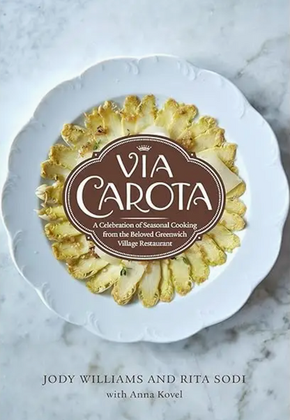 The cover of the Penguin Random House cookbook “Via Carota” showcases pineapple slices arranged in a circle on a white plate, with the product name and brand displayed in the center—a tribute to the beloved Greenwich Village restaurant.