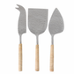 The Be Home Aquila Serving Collection features three handcrafted metal cheese knives with wooden handles, each with a unique blade shape—elegant pieces from India designed to elevate any cheese spread.