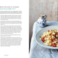 A bowl of pasta with squid, chickpeas, and cherry tomatoes rests on a blue plate beside a blue cloth napkin and a small white vase filled with yellow flowers. Inspired by the regional Italian recipes featured in Cucina Di Amalfi By Ursula Ferrigno from Simon & Schuster, this dish captures the flavors of the Amalfi Coast. Recipe text appears on the left.