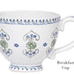 The Juliska Villa Seville Chambray Breakfast Cup features white ceramic with blue and green floral motifs, a handle, and a blue rim and base—an elegant piece from the Villa Seville Chambray Dinnerware Collection.