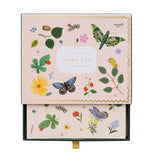 A box of thank you cards from the Curio Desk Accessory Collection by Riffle Paper Co., featuring botanical, butterfly, and illustrated bug designs—perfect for garden lovers. The partially open lid reveals beautifully coordinated cards inside.