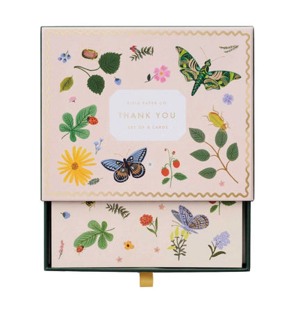 A box of thank you cards from the Curio Desk Accessory Collection by Riffle Paper Co., featuring botanical, butterfly, and illustrated bug designs—perfect for garden lovers. The partially open lid reveals beautifully coordinated cards inside.