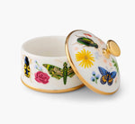 A porcelain box from the Curio Desk Accessory Collection by Rifle Paper Co., with a gold-rimmed lid ajar, features vibrant floral designs and whimsical bugs—a charming addition for garden enthusiasts.