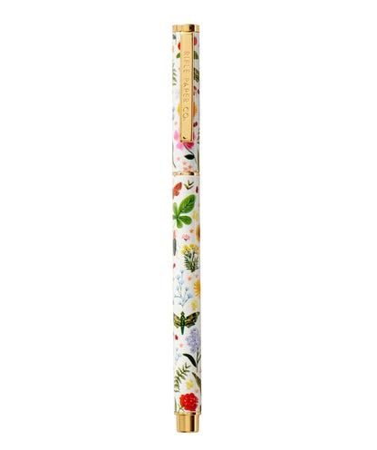 A white pen with gold accents from the Curio Desk Accessory Collection by Riffle Paper Co. features a vibrant floral and botanical design with illustrated bugs—great for garden lovers; clip displays the brand label.