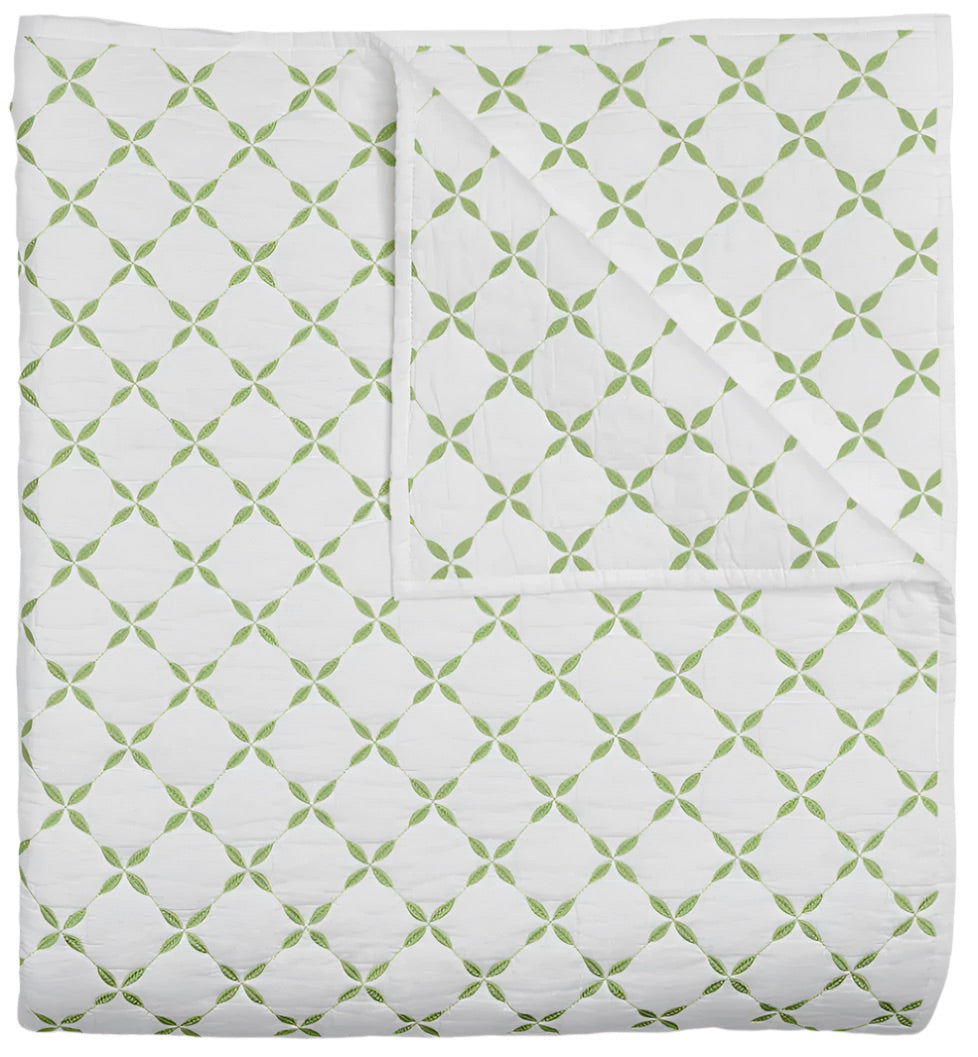 The Layla Bedding Collection by John Robshaw features a folded white quilt adorned with a repeating green geometric pattern inspired by Mughal gardens; the image displays both the front and a corner turned up to showcase the cotton voile backing.