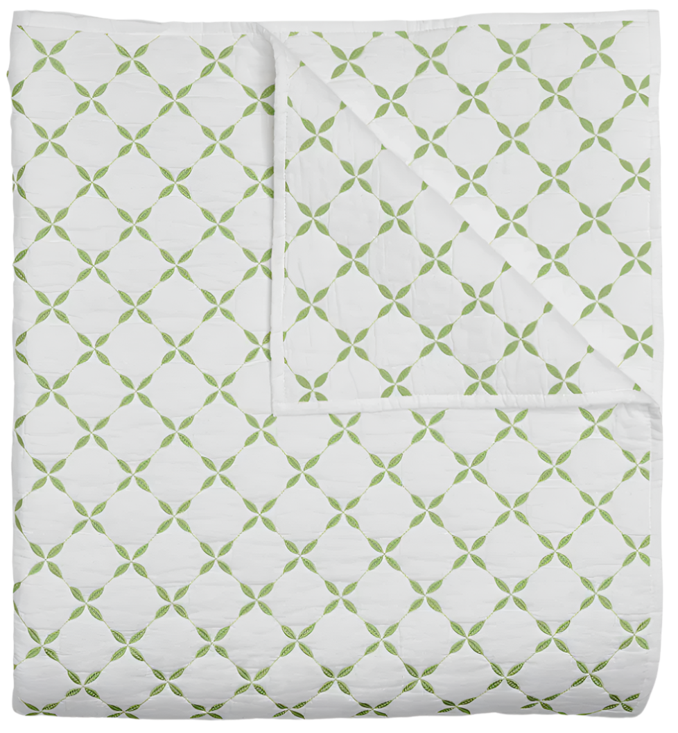 The Layla Leaf Coverlet by John Robshaw is a neatly folded white cotton voile quilt with a green geometric pattern inspired by Mughal gardens, shown with one corner turned back to reveal the same elegant design on the reverse.