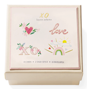 The Karen Adams XO Gift Enclosures set includes 8 hand-glittered cards in 2 styles with 8 envelopes, packaged in a cream-colored box with decorative art and "XO" and "love" accents.