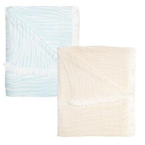 Two folded blankets from the John Robshaw Daasu Throw Collection feature fringed edging, one in light blue with a white striped pattern and the other in beige, made from soft stonewashed cotton.