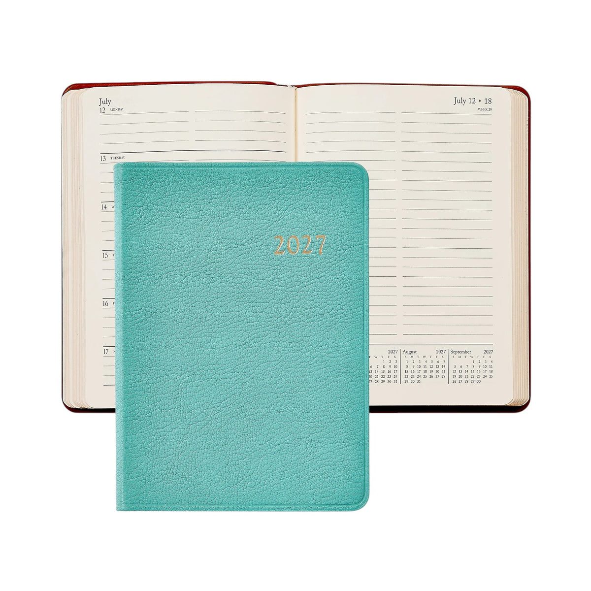 A turquoise 2027 Daily Journal from Graphic Image, featuring elegant gold lettering and ideal for use as an appointment book or diary, is pictured resting atop an open planner that reveals dated pages with lined sections and mini calendars.