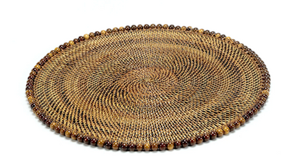 The Calaisio Round Placemat is handcrafted from natural vines and features a decorative border with alternating brown and tan beads, shown on a white background.