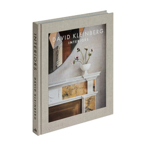 Interiors" by Phaidon is a hardcover book featuring a cover photo of a mantel with a vase of flowers, offering inspiration for luxury homes and sophisticated interior design.