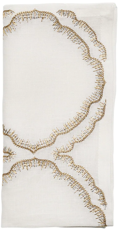 The Daydream Napkin Set by Kim Seybert features folded white napkins with a scalloped gold hand-embroidered design—ideal for elevating any table setting.