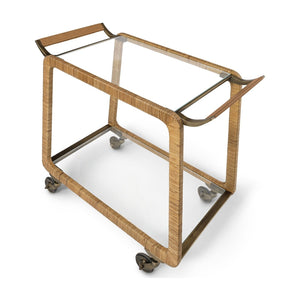 The Woodford Bar Cart by PALECEK features a rectangular design with a glass shelf top, wicker-wrapped frame, metal handles, and four caster wheels.