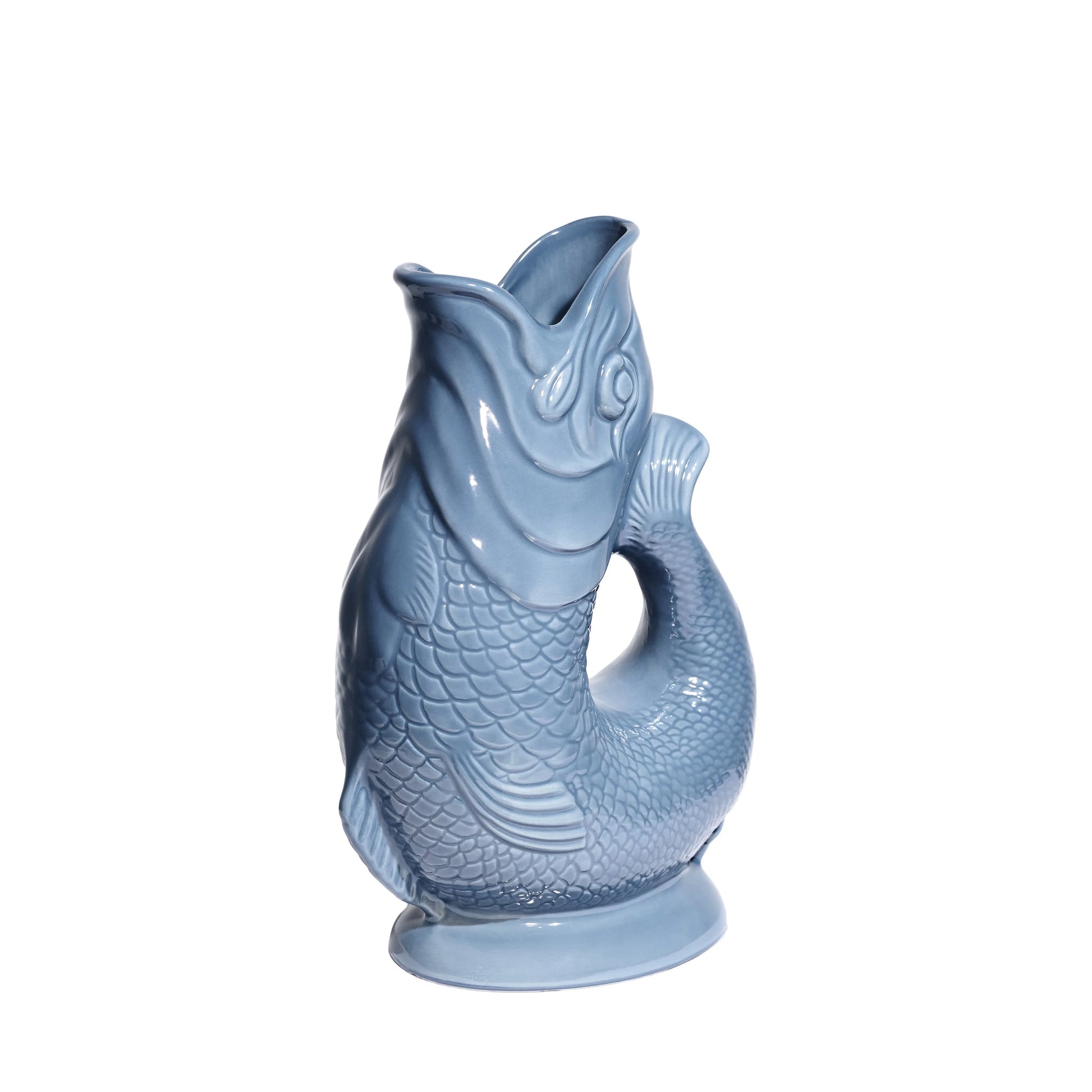 The Original Gluggle Jug’s Fish Gluggle Jug Collection features iconic ceramic fish-shaped pitchers in light blue with detailed scales and fins, standing upright—a true British design icon.
