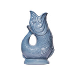 A glossy light blue Fish Gluggle Jug from The Original Gluggle Jug Collection, handmade in England and shaped like a fish with textured scales and a wide open mouth, is shown against a plain white background.