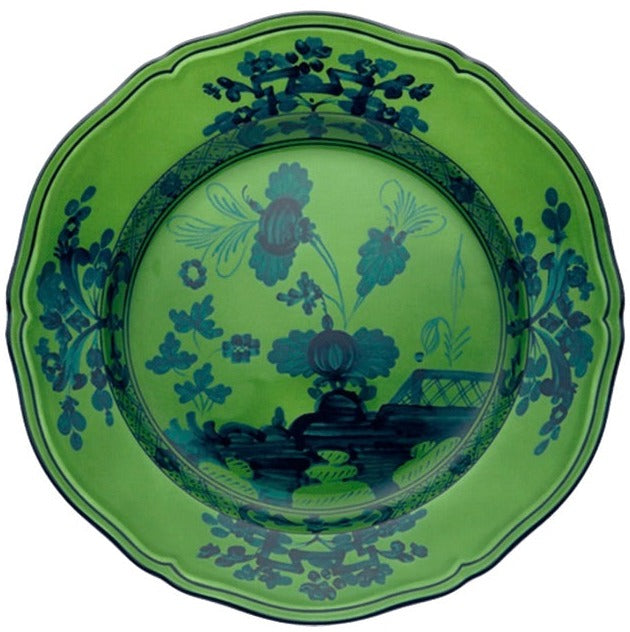 The Oriente Italiano Malachite Dinnerware Collection by Ginori 1735 features green ceramic plates with scalloped edges and blue floral and geometric patterns inspired by Faenza ceramics.