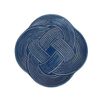 A round charger plate from the Juliska Le Panier Mystic Knot Denim Dinnerware and Serveware Collection, featuring a denim blue glaze and a white braided rope pattern in a symmetrical mystic knot design.