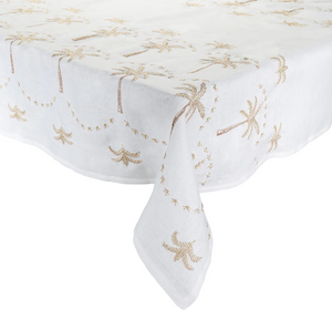 Kim Seybert Embroidered Palm Tablecloth with a golden starfish and seashell embroidery design, draped over a table with one corner hanging down.