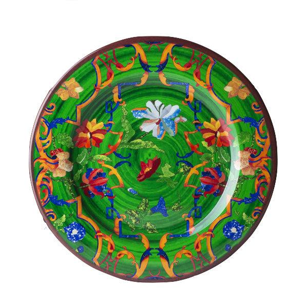 The Pancale Green Melamine Dinnerware Collection by Mario Luca Giusti features a round plate with a green background and vibrant red, yellow, blue, and orange floral and abstract patterns—modern antique style meets artistic design.