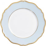 A round, white plate from Raynaud’s Mazurka Or Fond Bleu Gris Dinnerware Collection, featuring a light blue border, gold trim, and a scalloped edge design.
