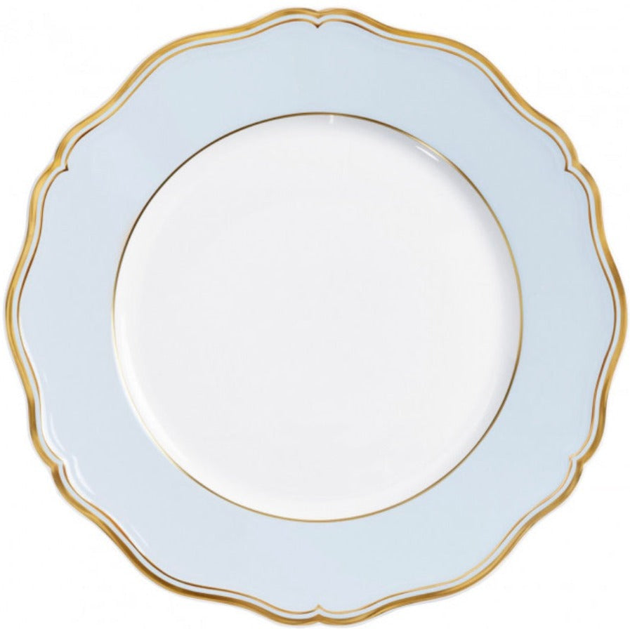 A round, white plate from Raynaud’s Mazurka Or Fond Bleu Gris Dinnerware Collection, featuring a light blue border, gold trim, and a scalloped edge design.