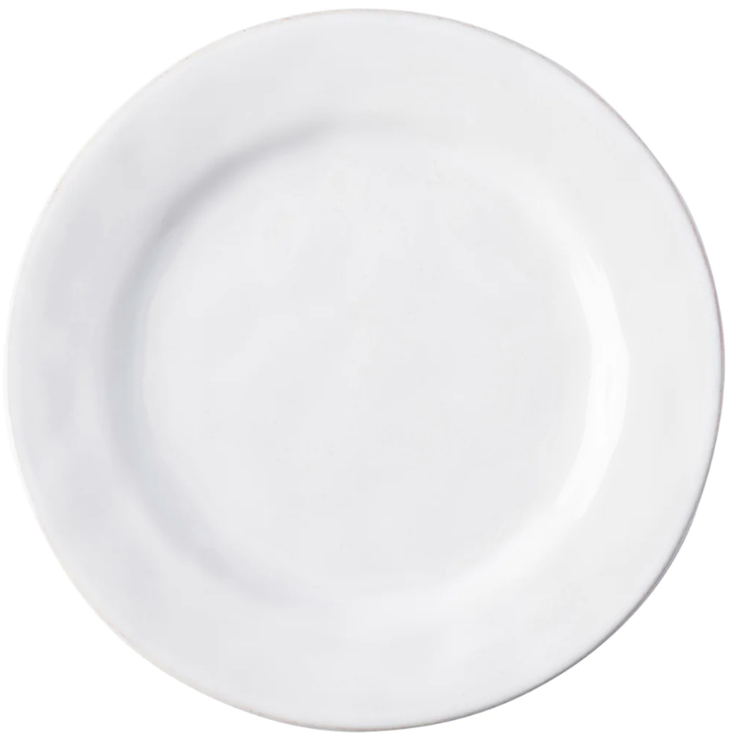 The Puro Whitewash Dinnerware Collection by Juliska features a plain, round, white ceramic plate photographed from above—an ideal neutral canvas for displaying teatime confections or savory tapas.
