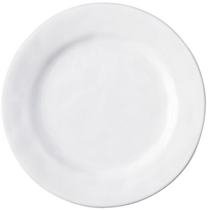 The Puro Whitewash Dinnerware Collection by Juliska features a plain, round, white ceramic plate photographed from above—an ideal neutral canvas for displaying teatime confections or savory tapas.