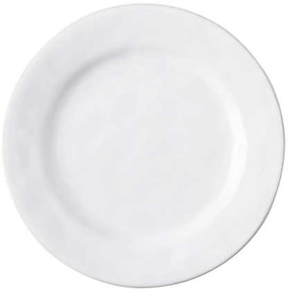 The Puro Whitewash Dinnerware Collection by Juliska features a plain, round, white ceramic plate photographed from above—an ideal neutral canvas for displaying teatime confections or savory tapas.