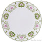 The Royal Crown Derby Cobblers Cove Camelot Dinnerware Collection offers a round white bone china dinner plate with a green and pink floral rim—ideal for luxury boutique hotel settings.