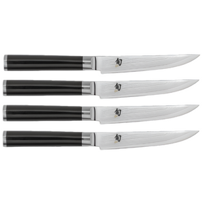A set of four steak knives from the Shun Classic Ebony series, featuring black handles and gleaming, razor-sharp steel blades, arranged in parallel.