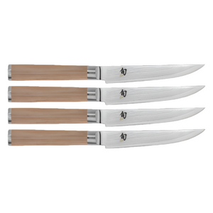A set of four Shun Classic Blonde steak knives, known for their razor-sharp edges and wooden handles, are arranged in parallel on a white background.