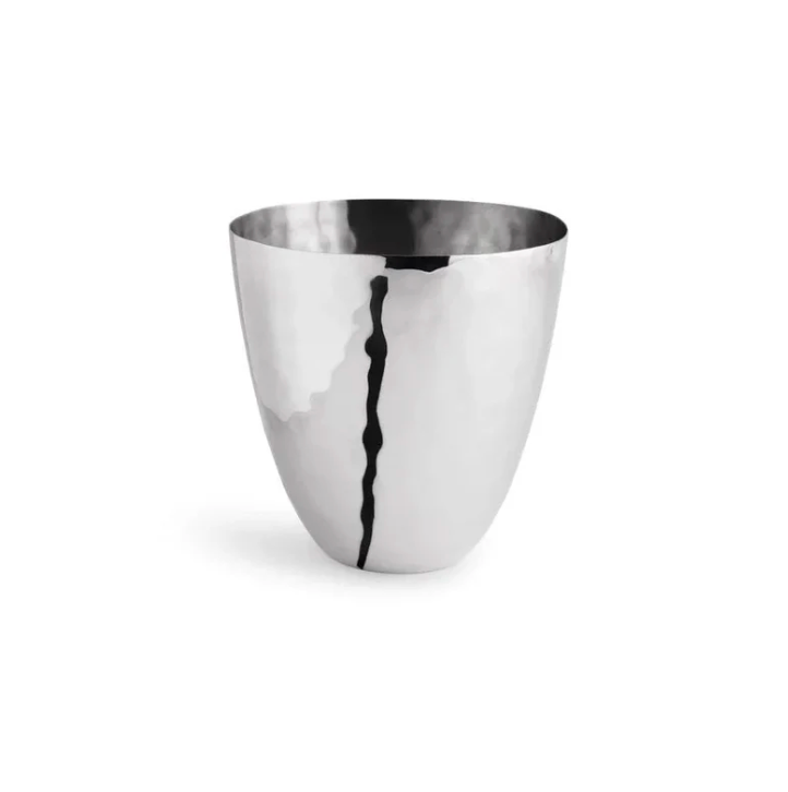 A polished stainless steel cup with a gently tapered silhouette and an irregular dark vertical line reflected on its surface, from the Reflective Bath Collection by Michael Aram—an elegant addition to your bathroom counter accessories—set against a plain white background.