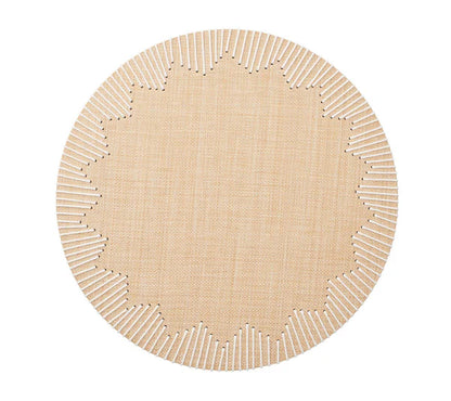 The Dream Weaver Placemat by Kim Seybert features a round, light tan woven design with white-stitched, starburst-style jagged edges—ideal for summer entertaining.
