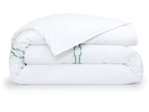 The Couture Tuileries Bedding Collection by Yves Delorme features a white PIMA cotton percale comforter with a simple green line motif, inspired by Tuileries Garden topiary, set on a crisp white background.
