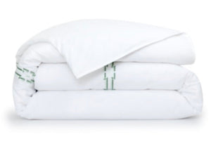 The Couture Tuileries Bedding Collection by Yves Delorme features a white PIMA cotton percale comforter with a simple green line motif, inspired by Tuileries Garden topiary, set on a crisp white background.