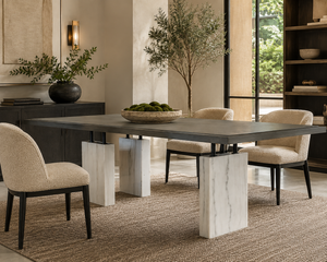 Modern dining room with the Block Dining Table by Hickory Chair—a rectangular minimalist piece featuring striking marble legs—paired with four upholstered chairs, a decorative bowl of moss, a large plant, and neutral-toned decor.