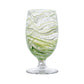 The Puro Marbled Drinkware Collection by Juliska features a clear glass goblet with green and white seaglass-inspired swirls, set on a short stem and round base, displayed against a plain white background.