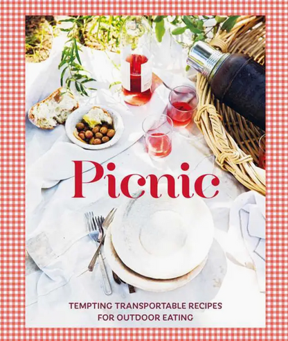 A picnic scene featuring plates, cutlery, bread, olives, drinks, and a thermos on a white cloth is shown alongside the text: “Picnic” by Simon & Schuster—tempting transportable recipes for outdoor dining.