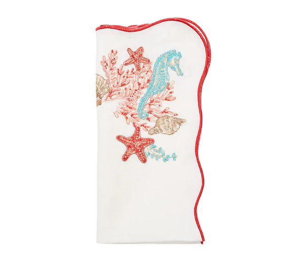 The Kim Seybert Marina Napkin Set features white cloth napkins with red trim and embroidered seahorse, starfish, coral, and seashells—perfect for adding a coastal touch to your table.