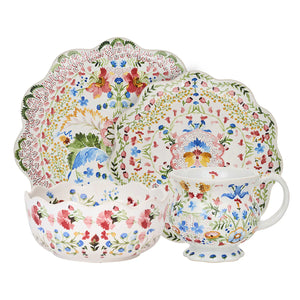The Sofia Serveware Collection by Juliska includes four scalloped-edge pieces—a plate, salad plate, bowl, and mug—each showcasing vibrant colors and a whimsical floral design with romantic ruffled edges.