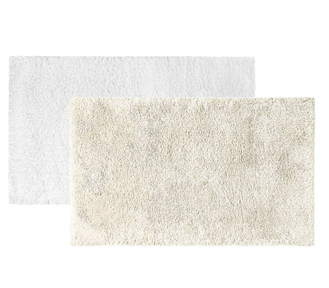 Two Egoist Cloud Bath Rugs by Graccioza, one white and one beige, made from soft Egyptian cotton, are arranged overlapping on a plain white background.