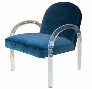 A blue upholstered chair in Vintage Navy, featuring a round backrest and clear, curved acrylic armrests and legs—a statement piece that embodies the refined elegance of the Elva Acrylic Arm Chair by Highland House.