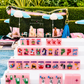 Bespoke x Gray Malin Mahjong Collection set with pink tiles featuring travel icons and dogs, arranged on racks in front of a zippered pouch printed with a beach scene.