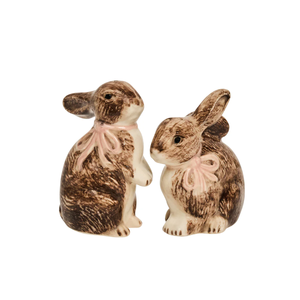 The Clever Creatures Bunny Salt and Pepper Set by Juliska features two hand-painted ceramic bunnies with brown and white fur and pink neck ribbons, facing each other—perfect for your table.